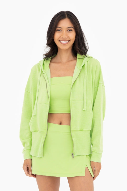 Woman wearing a neon green outfit with a fleece jacket, top, and skirt on a white background