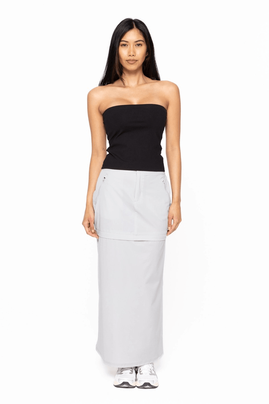 Woman wearing a black strapless top and light gray skirt on a white background